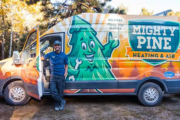 Mighty Pine service truck with a smiling technician standing next to the truck.
