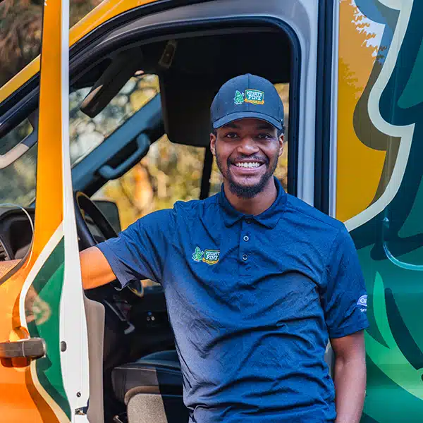 Mighty Pine service truck with a smiling technician standing next to the truck.