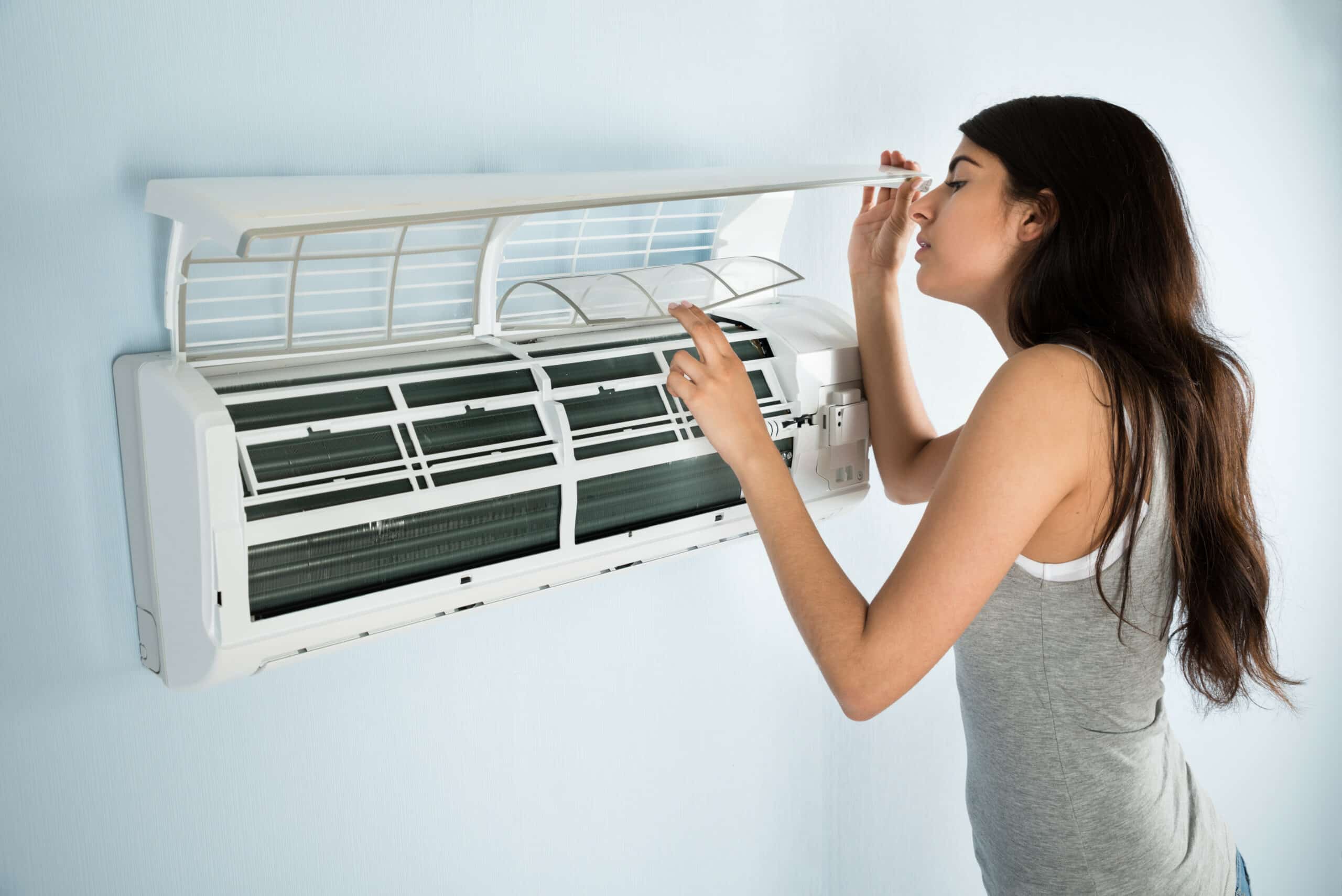 Woman checking ductless HVAC system in Arvada, CO.