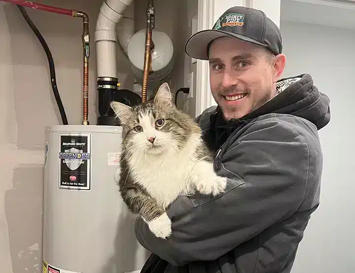 Mighty Pine technician standing in front of boiler with a cat in Arvada, CO.