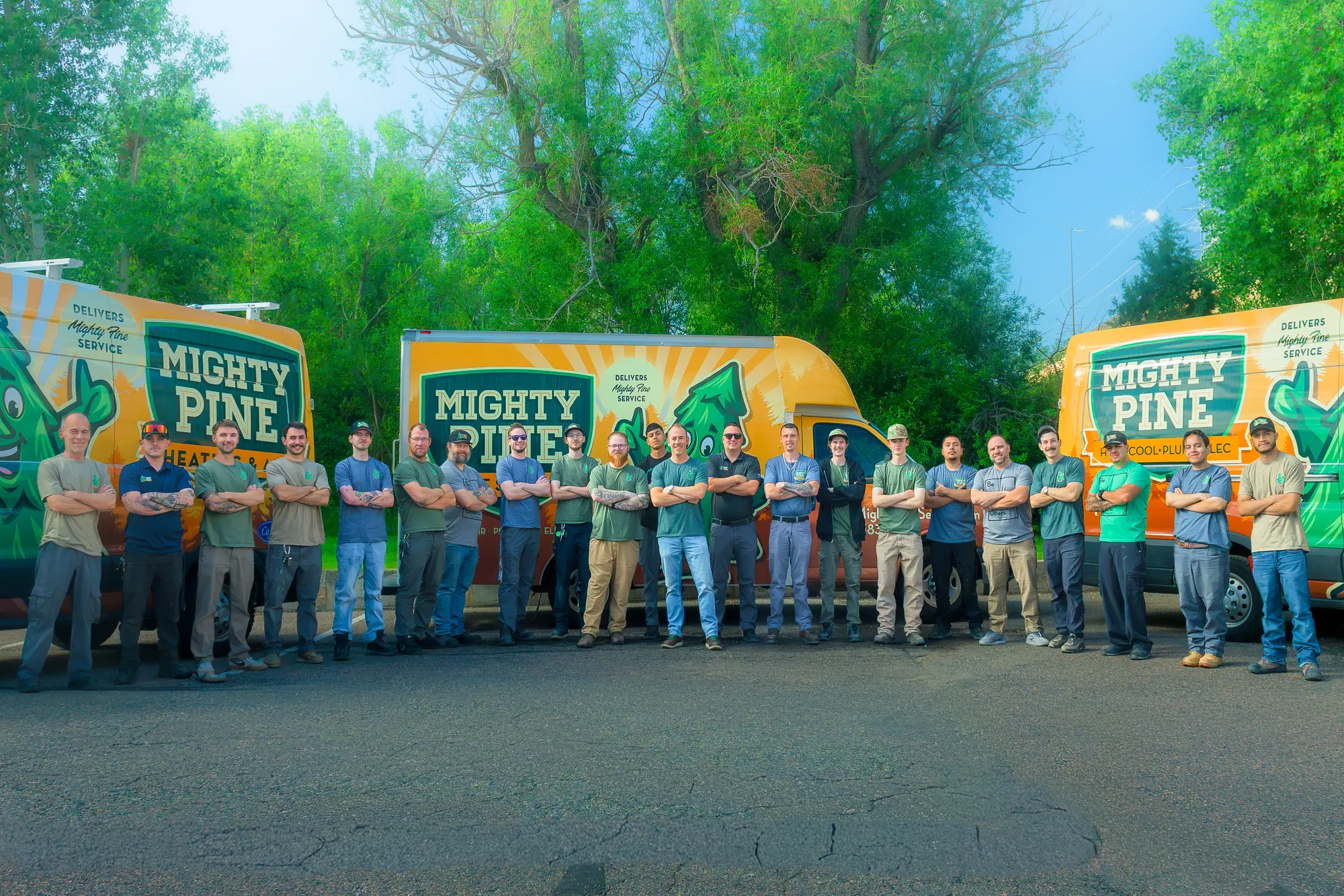 The Mighty Pine Home Services team standing in front of their fleet of service vans.