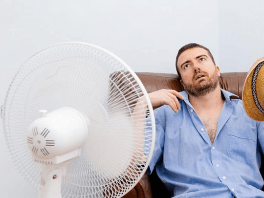 man fanning himself, trying to cool down because AC isn't working