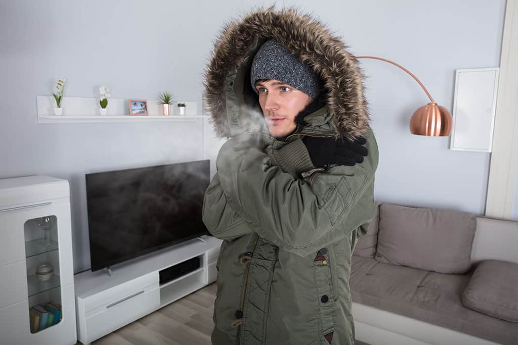 Young Man With Warm Clothing Feeling The Cold Inside House