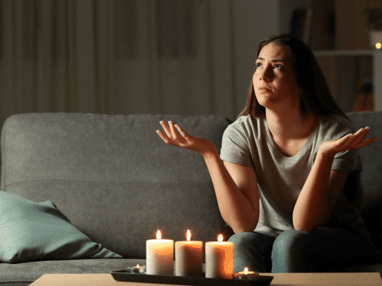 woman sitting in a dark living room with lit candles during a power outage